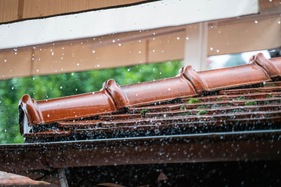 Regen läuft über eine Dachrinne an einem Wohnhaus